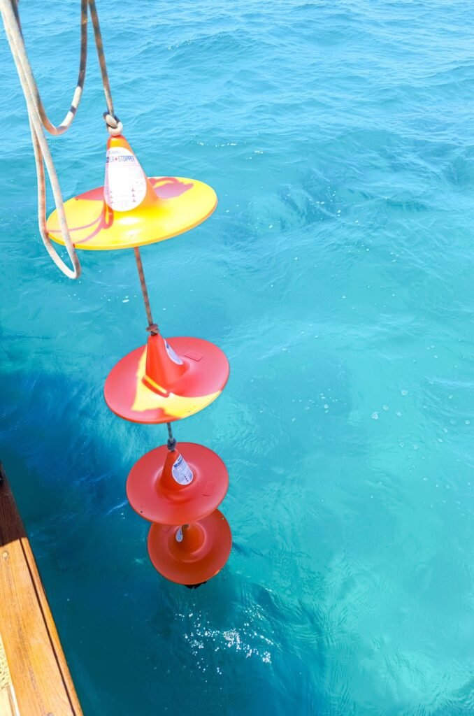 Boyas luminosas rojas y amarillas flotando sobre el agua turquesa junto al casco