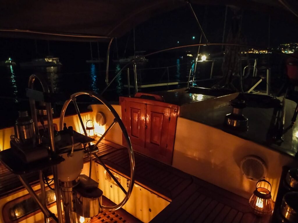 Bañera de un velero de noche, con farolillos encendidos y la rueda del timón