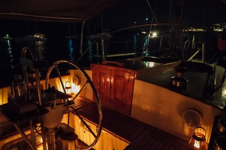 Bañera de un velero de noche, con farolillos encendidos y la rueda del timón